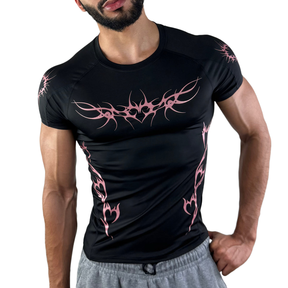 Model wearing black workout tee with vibrant pink tattoo-style graphics and heart tribal accents