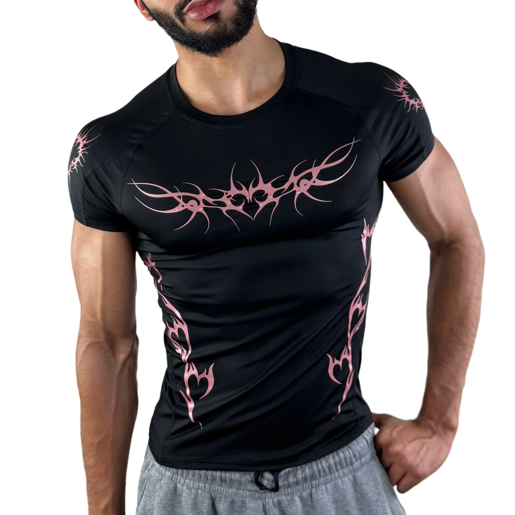 Model wearing black workout tee with vibrant pink tattoo-style graphics and heart tribal accents