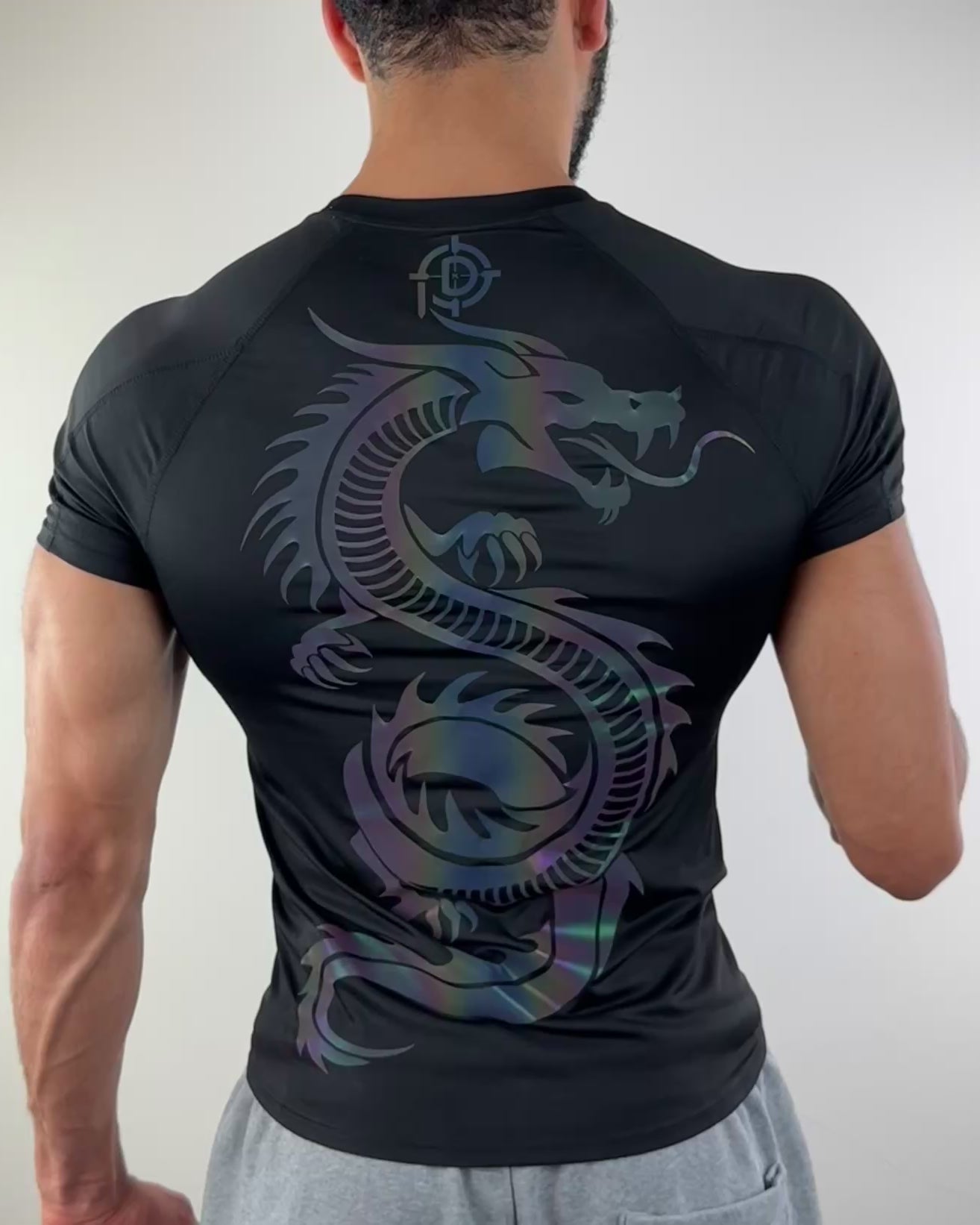 Video of a man wearing a black athletic shirt with a large colorful dragon design on the back, shown from the rear view