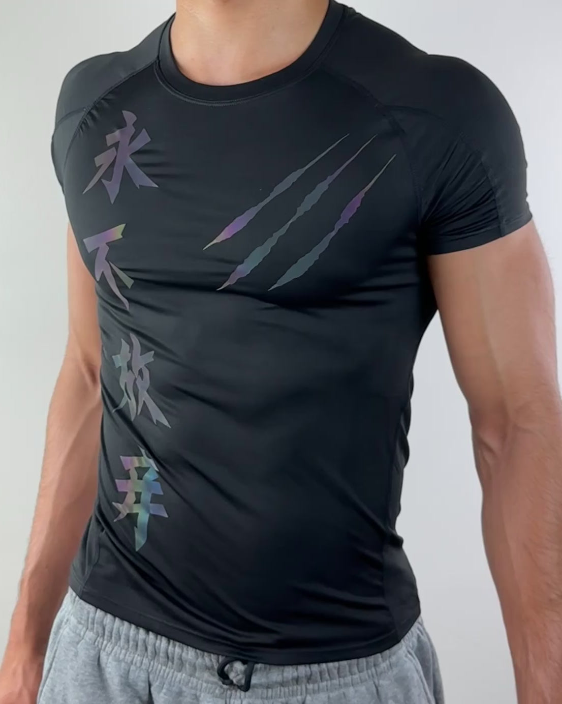 Video of a man wearing a black athletic shirt featuring colorful vertical characters and claw mark designs on the front, shown from the front view